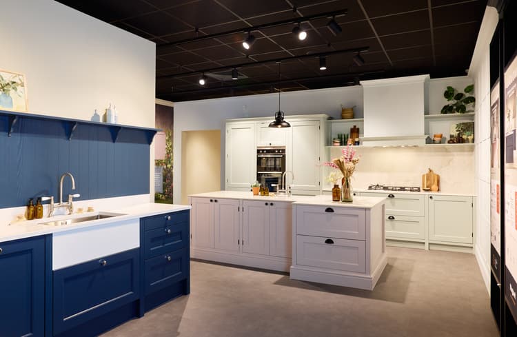 Modern kitchen display featuring blue and white cabinetry, a central island, and stylish decor elements.