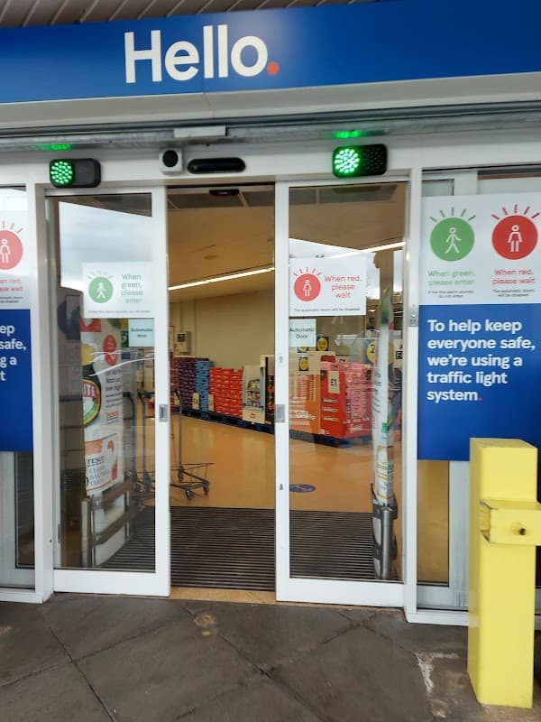 Entrance to Tesco Superstore with traffic light system signs and green/red indicators for safety.
