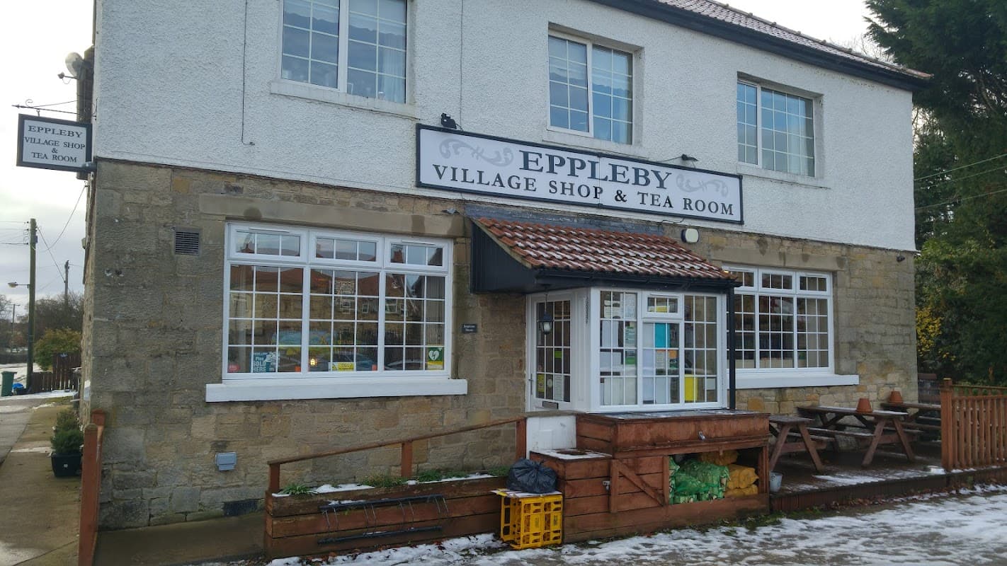 Eppleby Village Shop with a stone facade, large windows, and outdoor seating area in a quaint Yorkshire setting.