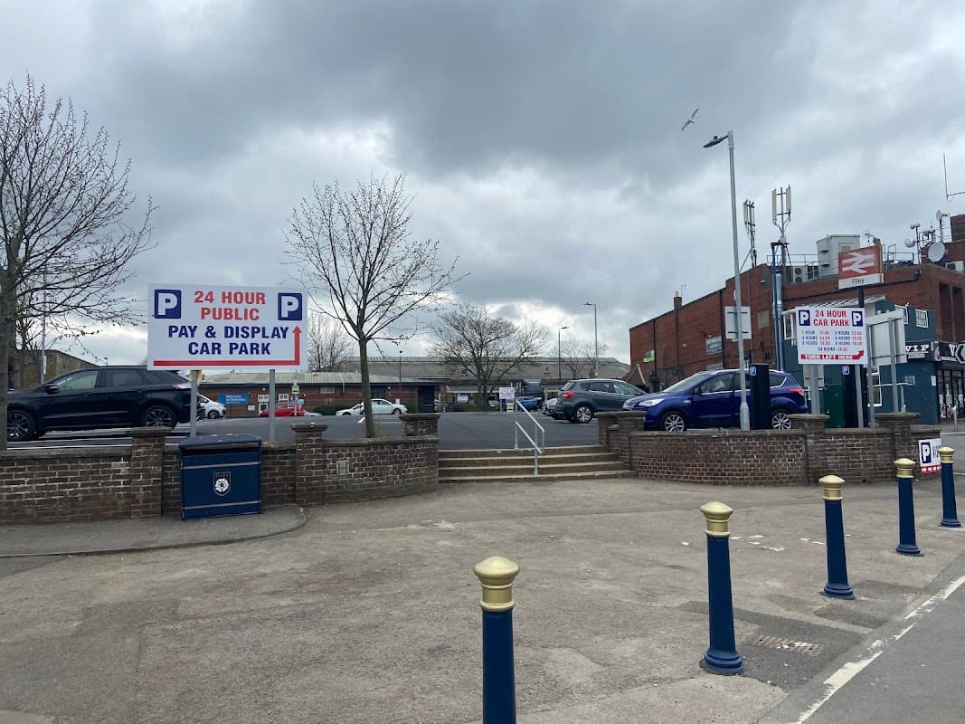 24-hour public pay and display car park with signs, parked cars, and cloudy sky in Filey, Yorkshire.