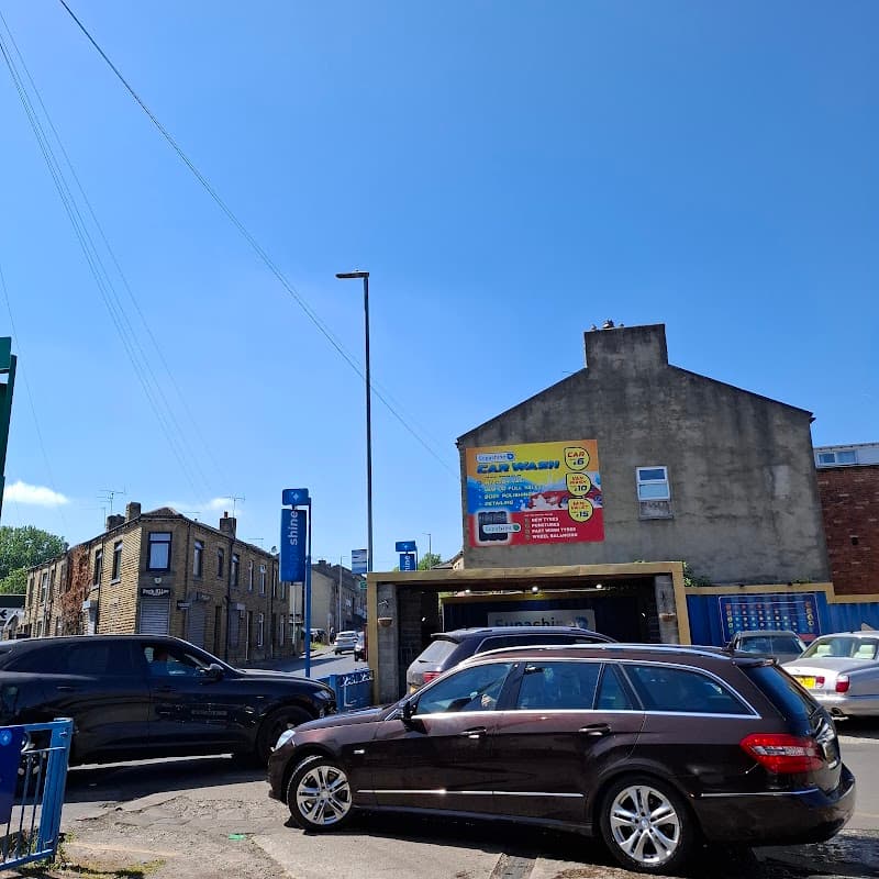 Bright blue sky over SUPA SHINE HAND CAR WASH AND VALETING, with cars parked and a building in Liversedge, Yorkshire.