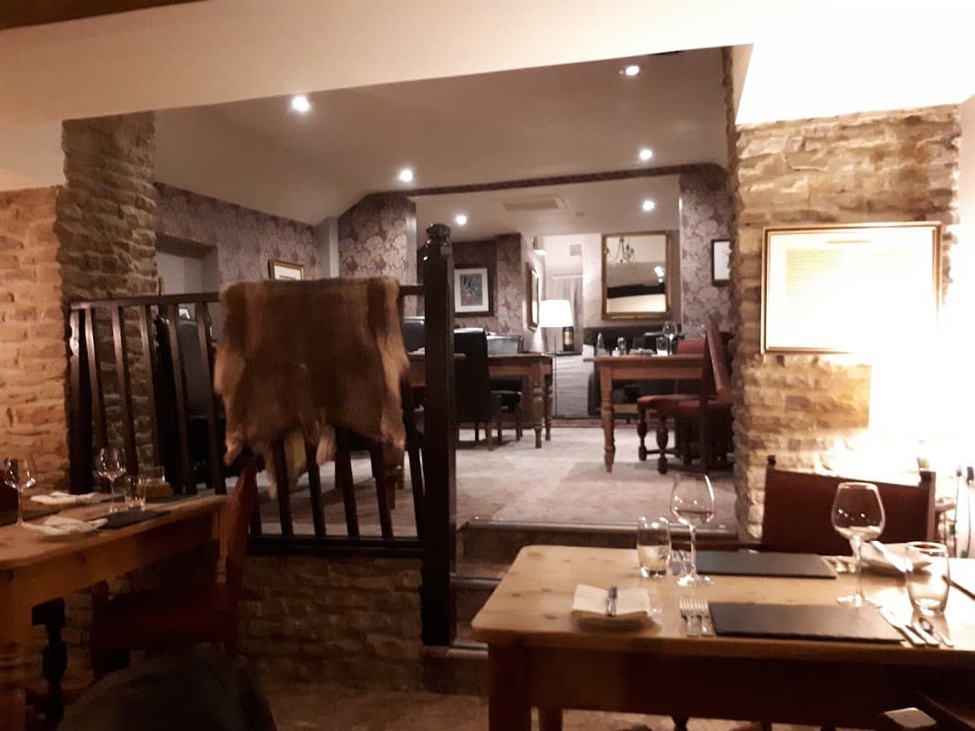 Cozy interior of The Hare Restaurant with wooden tables, stone walls, and elegant dining setup in Old Byland, Yorkshire.