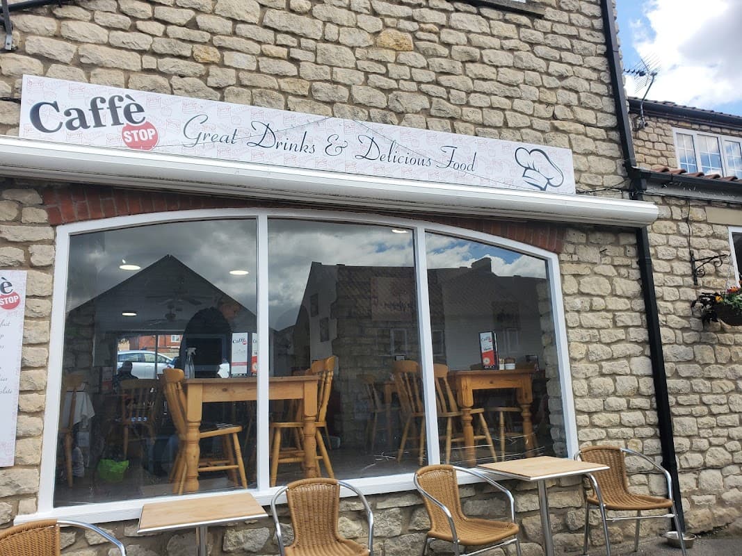 CaffΓ© Stop Pickering features a stone exterior, large windows, wooden tables, and outdoor seating.