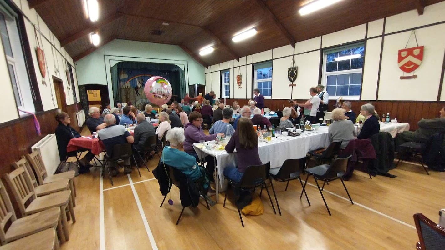 A lively gathering in Slingsby Village Hall with tables set for dining and decorations, featuring a large balloon.