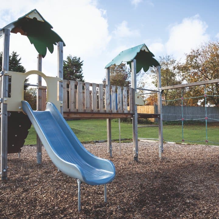 Playground at Haven Primrose Valley Holiday Park featuring a slide, climbing structure, and surrounding grass area.