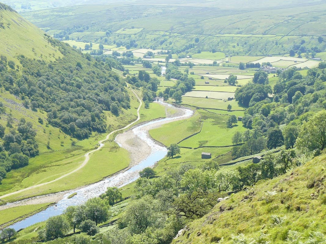 Scenic view of rolling green hills, a winding river, and lush farmland in Thwaite, North Yorkshire.