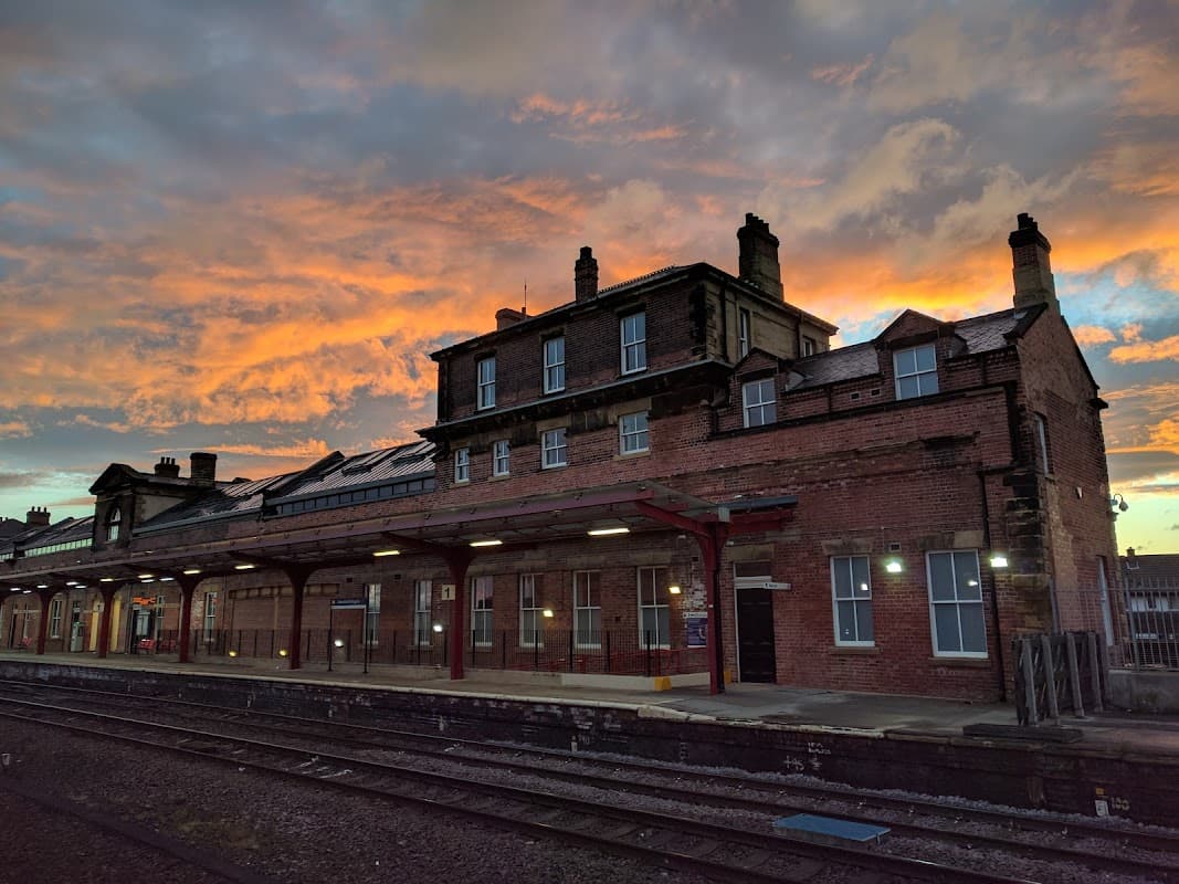Sunset casts vibrant colors over Wakefield Kirkgate station, highlighting red-brick architecture and railway tracks.