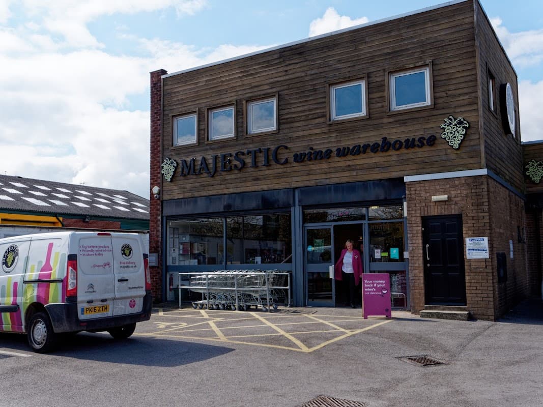Majestic Wine warehouse with wooden exterior, large windows, outdoor seating, and a delivery van parked outside.