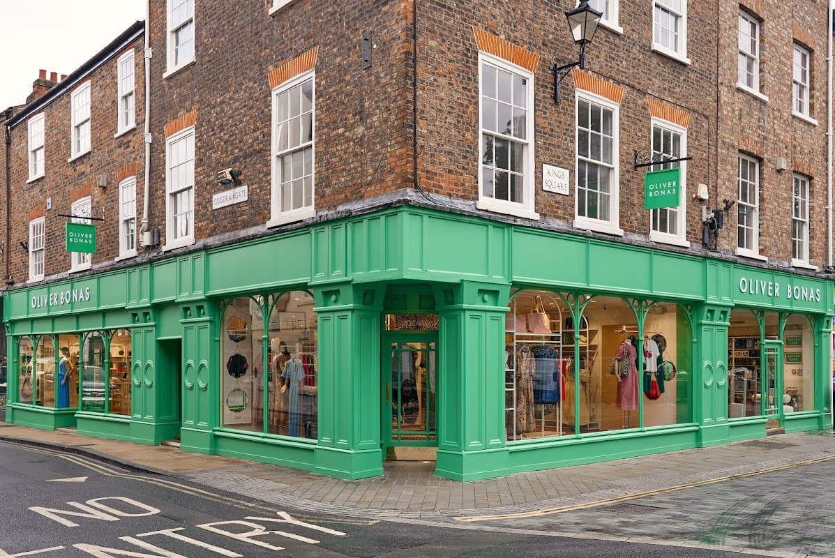 Green storefront of Oliver Bonas with large windows displaying colorful clothing and accessories in York, Yorkshire.