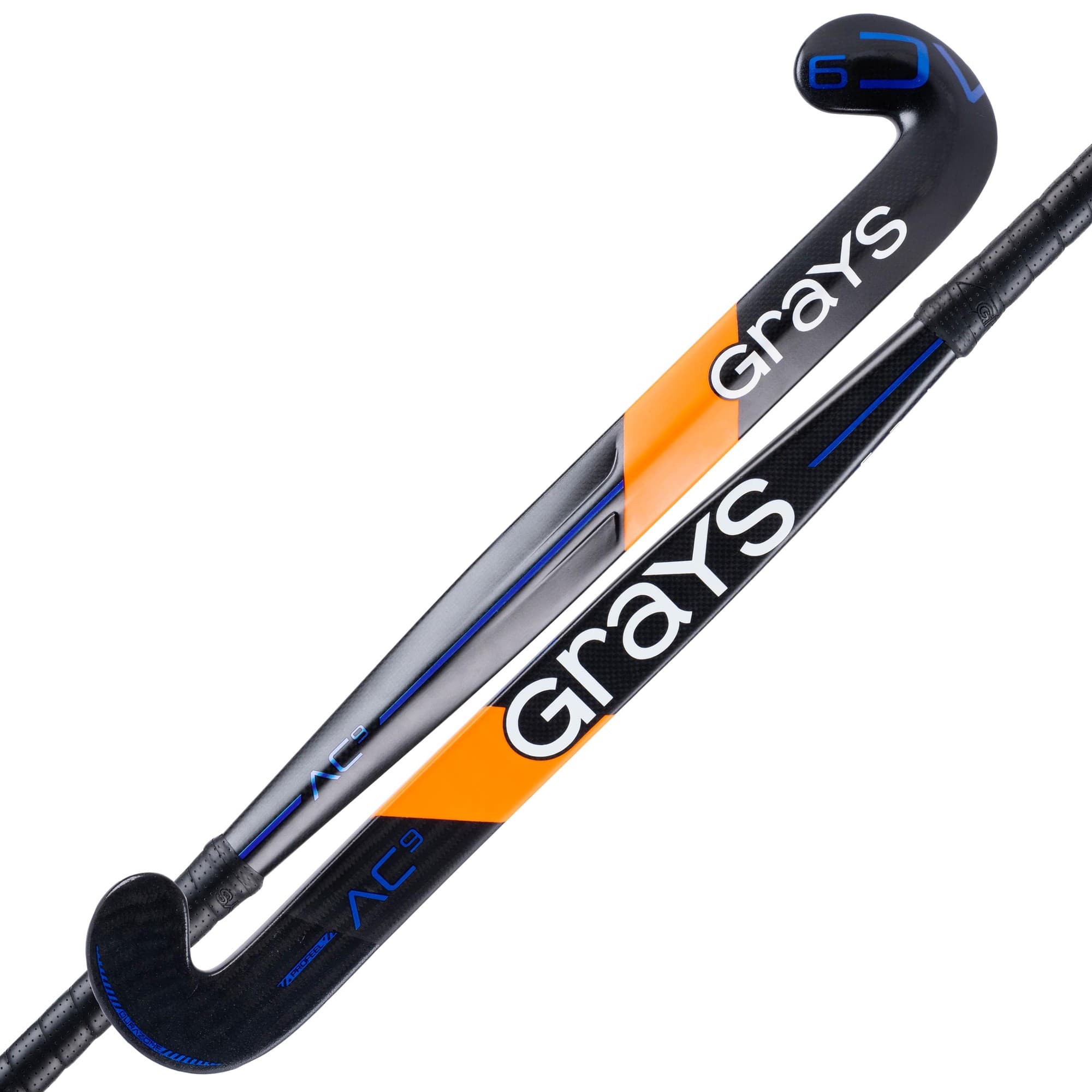 Black and orange composite hockey stick with a curved design, featuring "Grays" branding prominently displayed in white and blue accents, designed for enhanced performance.