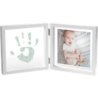 White hinged frame with a baby photo on one side and a green handprint on the other.
