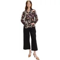 Floral print blouse with long sleeves, dark background, and vibrant pink and beige flowers, worn by a woman.