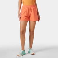 Orange Helly Hansen women's shorts, 4-inch length, elastic waistband, lightweight fabric, worn by model with teal shoes.