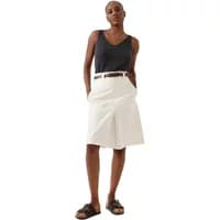 White knee-length Artlove Neline skirt with pleats, worn with a black striped tank top and brown belt.