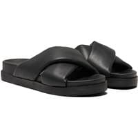 Black polyurethane women's mules with wide crisscross straps and flat soles.