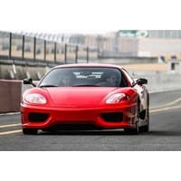Red Ferrari 360 supercar on a racetrack, sleek design with prominent headlights and aerodynamic curves.