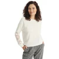 White women's sweatshirt with floral embroidery on sleeves, worn by model with curly hair and plaid pants.
