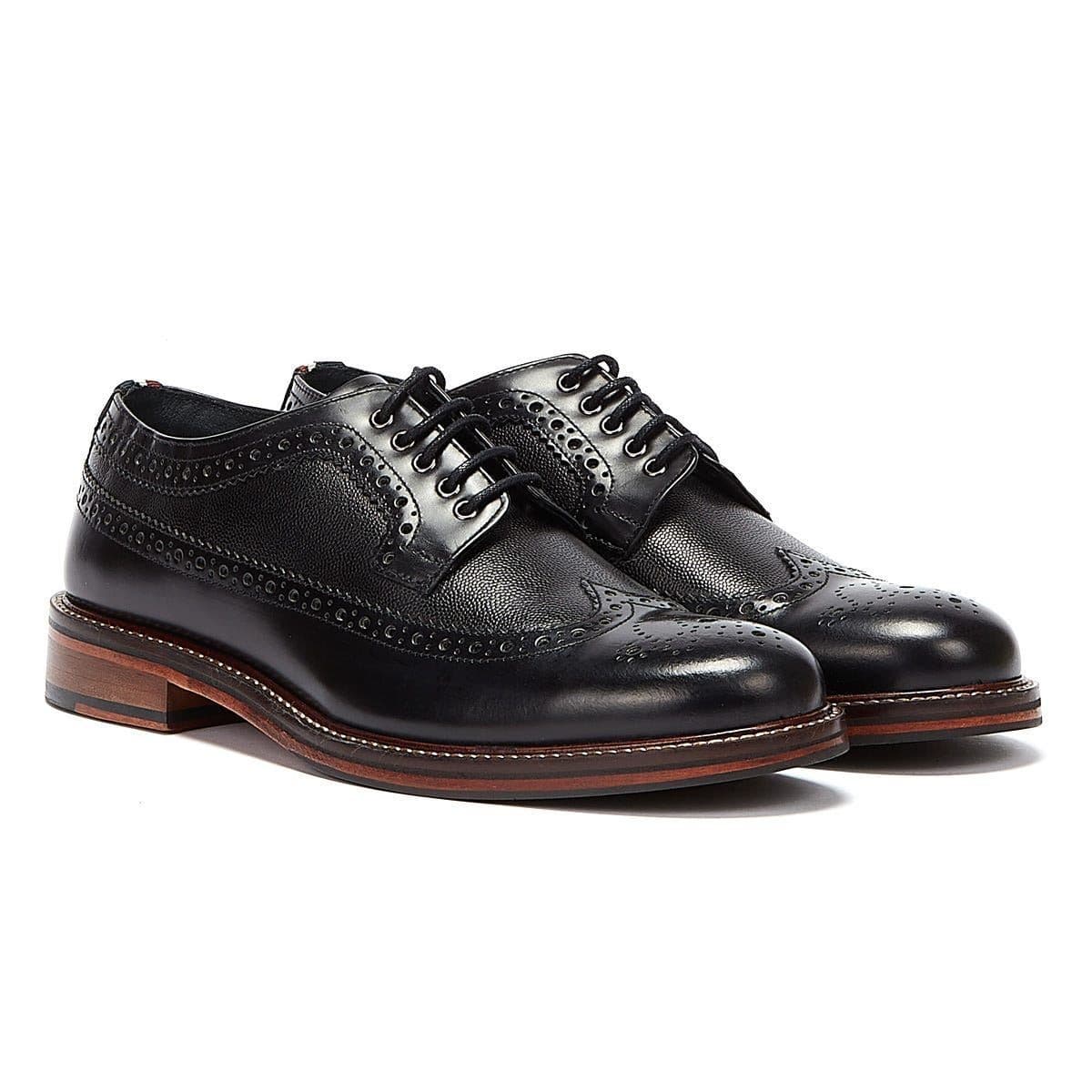 Black leather lace-up brogue shoes featuring intricate perforated detailing and a classic design, with a contrasting brown wooden sole.