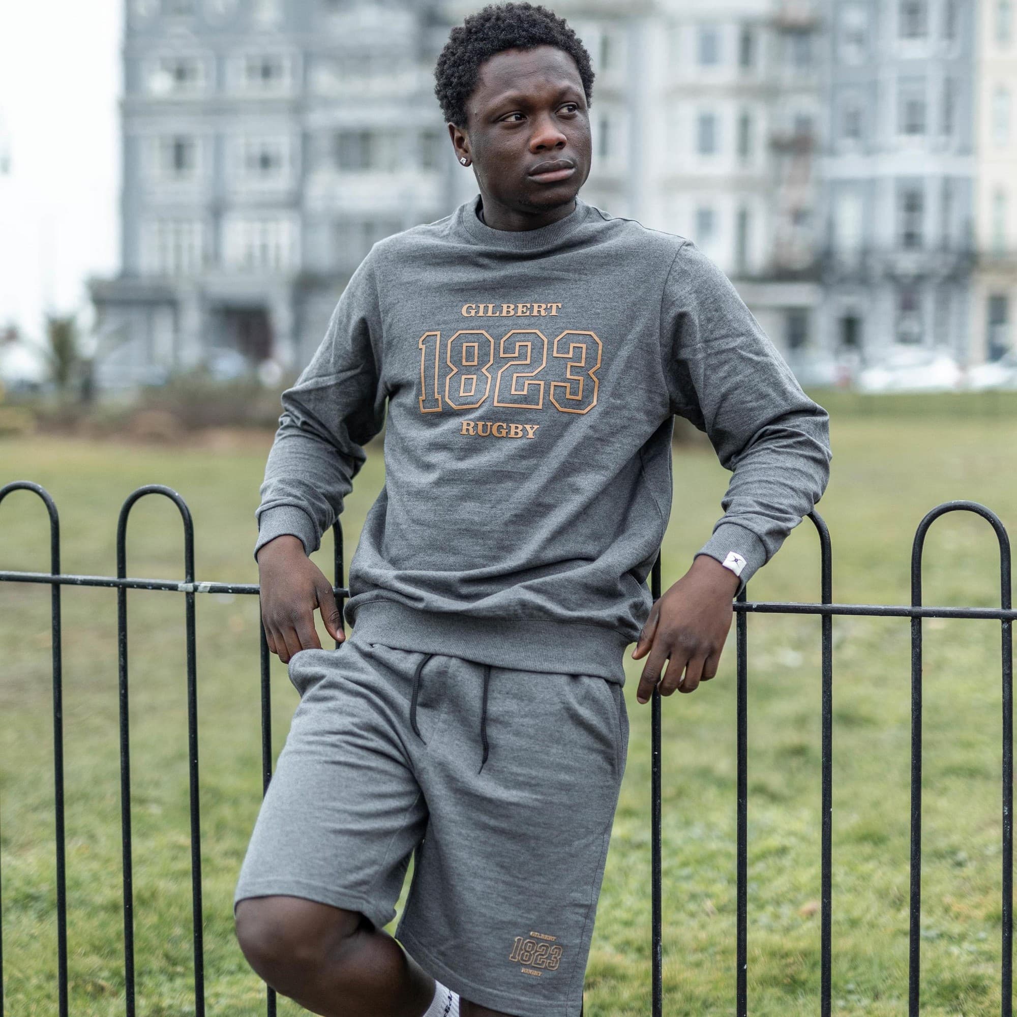 Grey leisure shorts made from soft material, featuring an elastic waistband and side pockets, with "1823" and "RUGBY" embroidered in gold on the front.