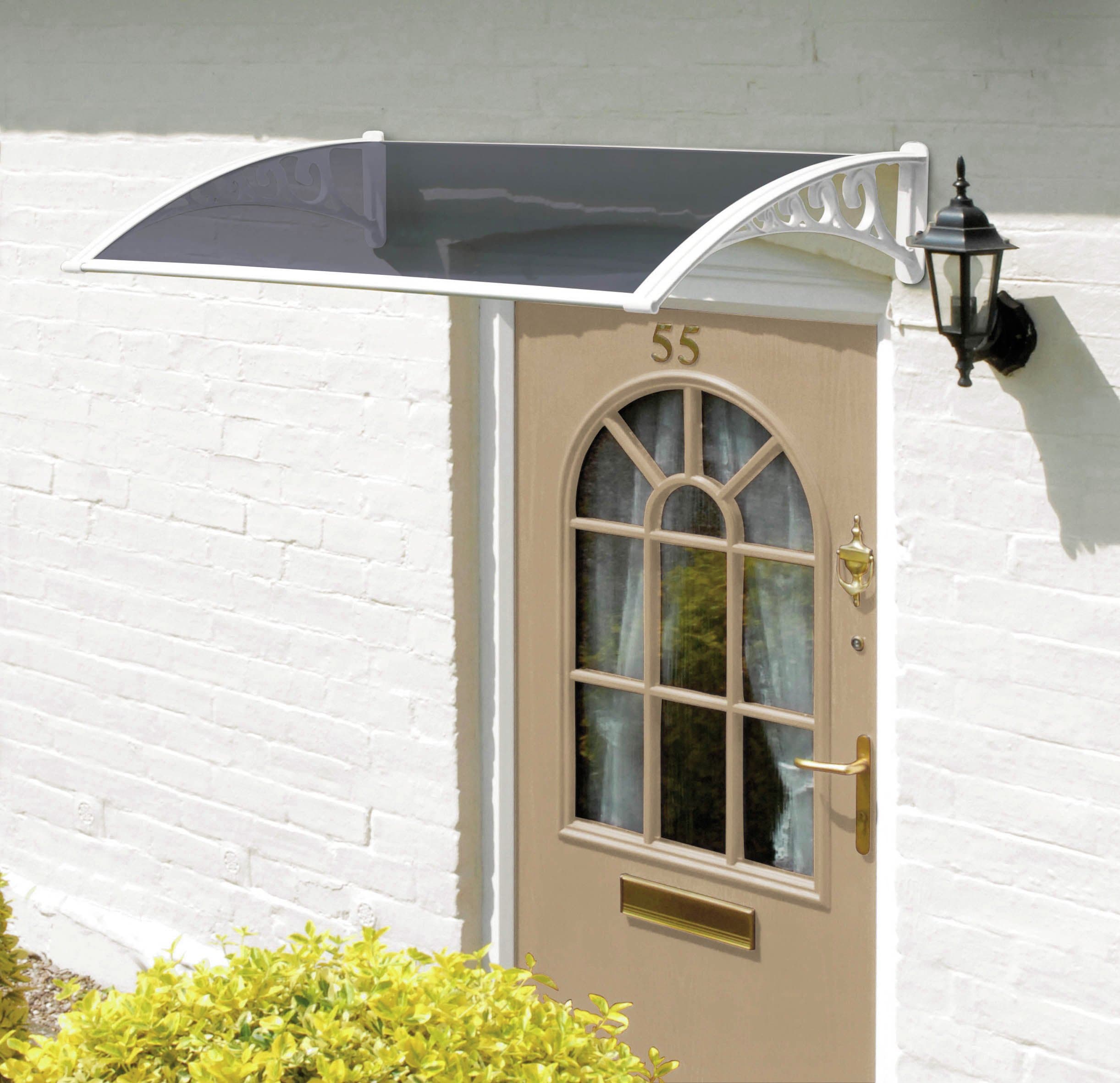 Tinted white 1m door canopy by Greenhurst features a curved design with decorative brackets, mounted above a light brown door with a glass panel and a wall-mounted lantern.