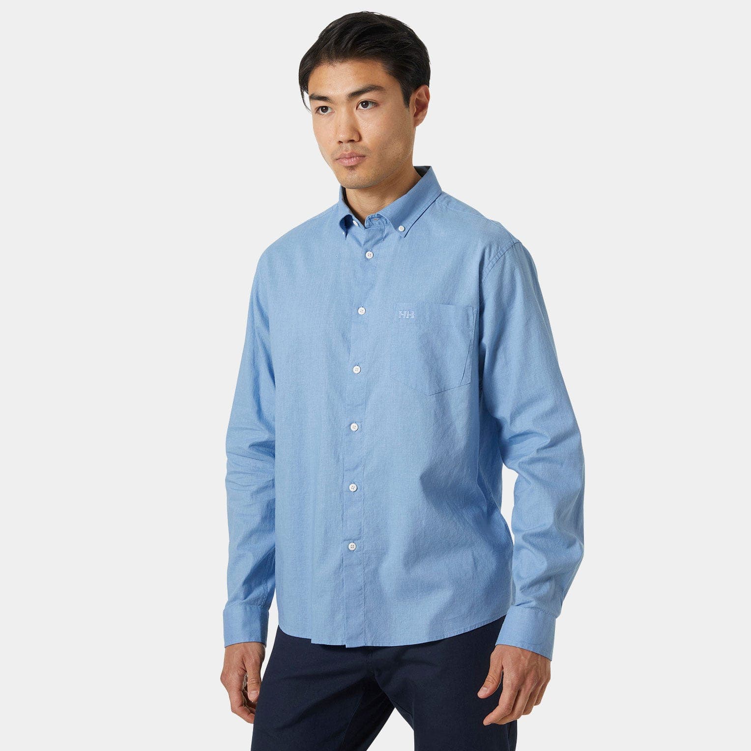Light blue long-sleeve button-up shirt made of cotton, featuring a chest pocket and a subtle Helly Hansen logo on the left side.