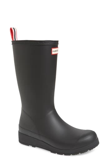 Black rubber tall rain wellies for women by Hunter, featuring a red and white logo tab at the back and a sturdy sole for traction.