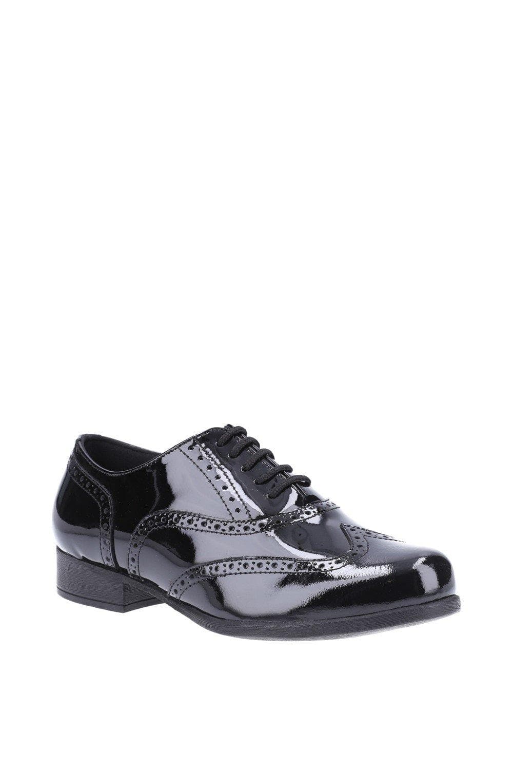 Black patent leather brogues for junior girls featuring intricate perforated detailing, a classic lace-up design, and a low heel for comfort.