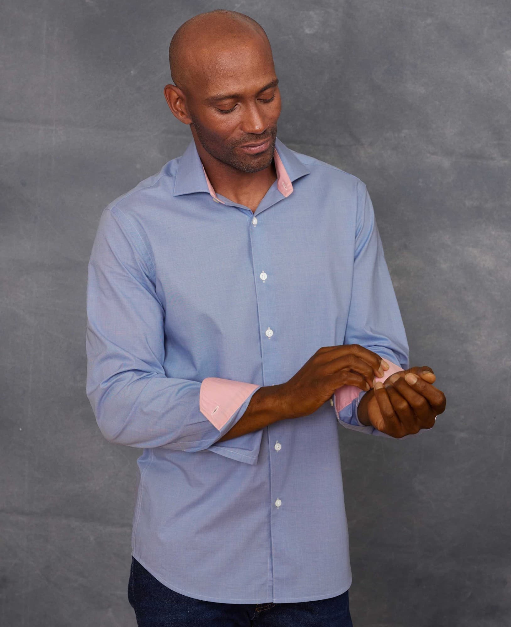 Men's navy cotton micro dobby slim fit shirt featuring a single cuff, contrasting pink inner collar, and long sleeves, displayed on a model adjusting the cuff.