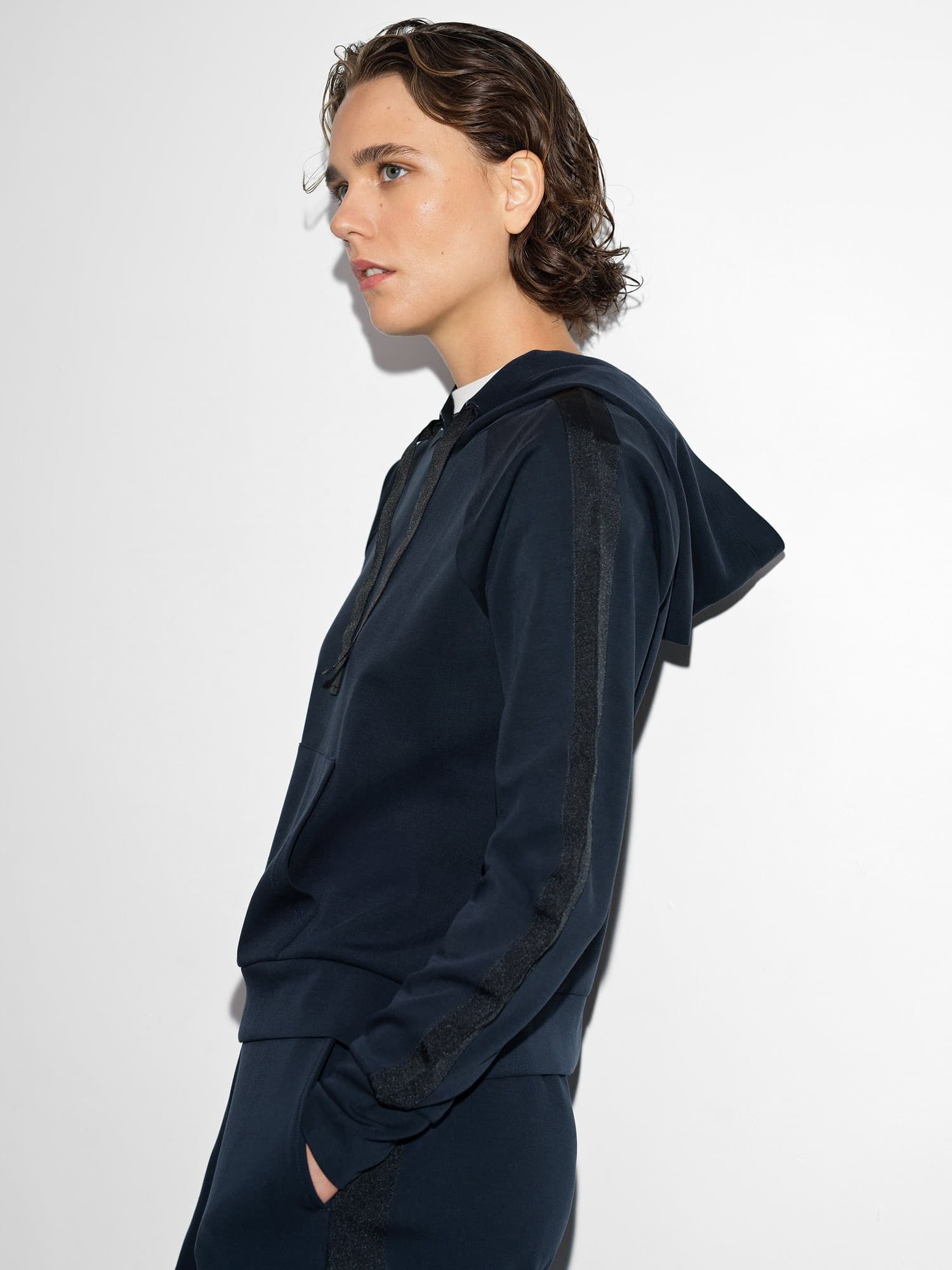 Navy hoodie with black trim details, featuring a drawstring hood, long sleeves, and a relaxed fit, made from soft material, styled on a model against a plain background.