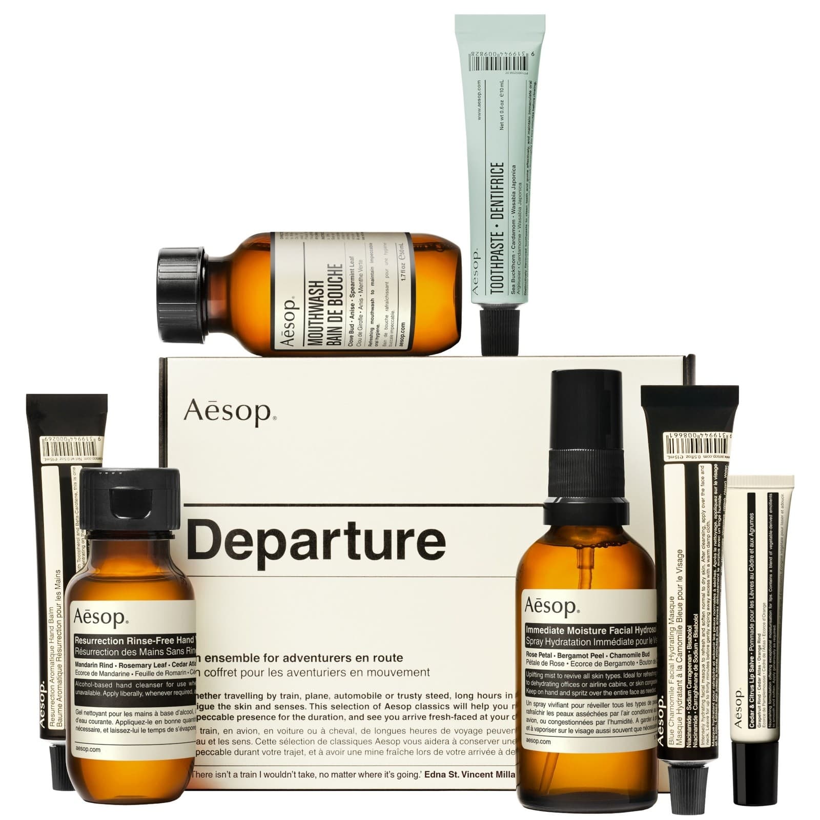 A collection of Aesop travel-sized body care products in amber glass bottles and tubes, featuring a beige box labeled "Departure" and various labeled skincare items.