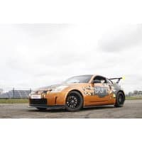 Orange sports car with "Drift" logo, black wheels, and rear spoiler on a track for driving experience.
