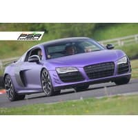 Purple Audi R8 V10 on a racetrack, sleek design, black grille, and alloy wheels, part of a driving experience package.