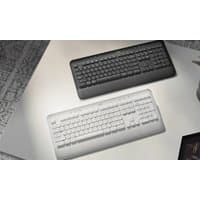 Black and white Logitech SIGNATURE K650 keyboards with ergonomic design and full-size layout on a desk.