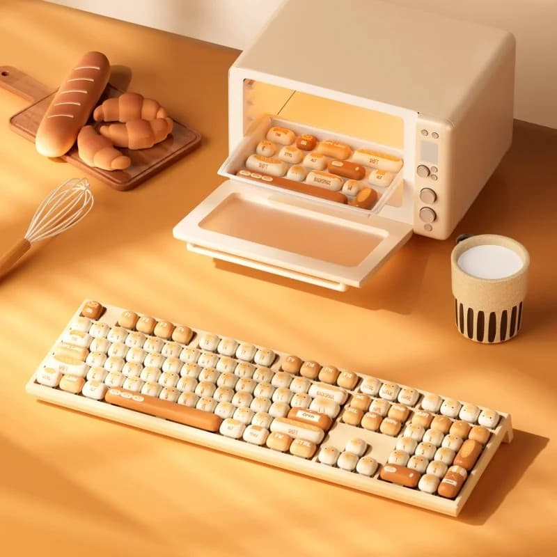 A beige keyboard with watermelon-themed keycaps, featuring a mix of cream and orange colors, sits beside a small oven-like container and kitchen utensils on a warm, orange surface.