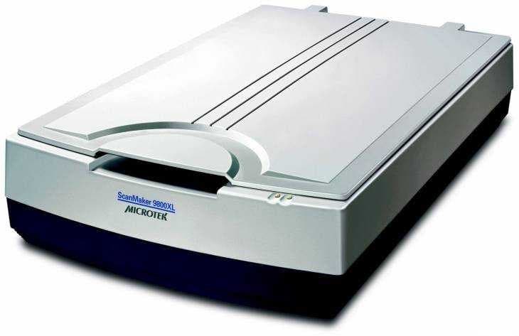 Microtek ScanMaker 9800XL Plus scanner in gray and black, featuring a sleek, flat design with a curved top and control buttons on the front, capable of 1600 x 3200 DPI resolution.