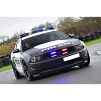 Black and white V8 GT Mustang police car with red and blue lights on track.