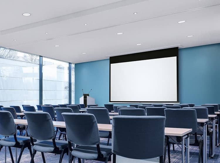 Sapphire AV SESC180B1610-A2 projection screen, 79" in size, features a sleek black frame and is mounted in a modern conference room with blue walls and rows of blue chairs.