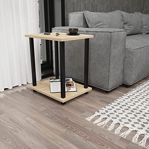 Black and oak-patterned industrial cocktail table with a square top, supported by black metal legs, featuring a lower shelf, placed beside a gray couch on a wooden floor.