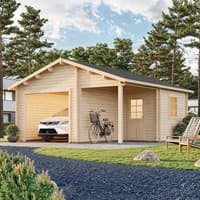 Wooden log cabin garage with double doors, pitched roof, and side window, surrounded by trees and a gravel path.