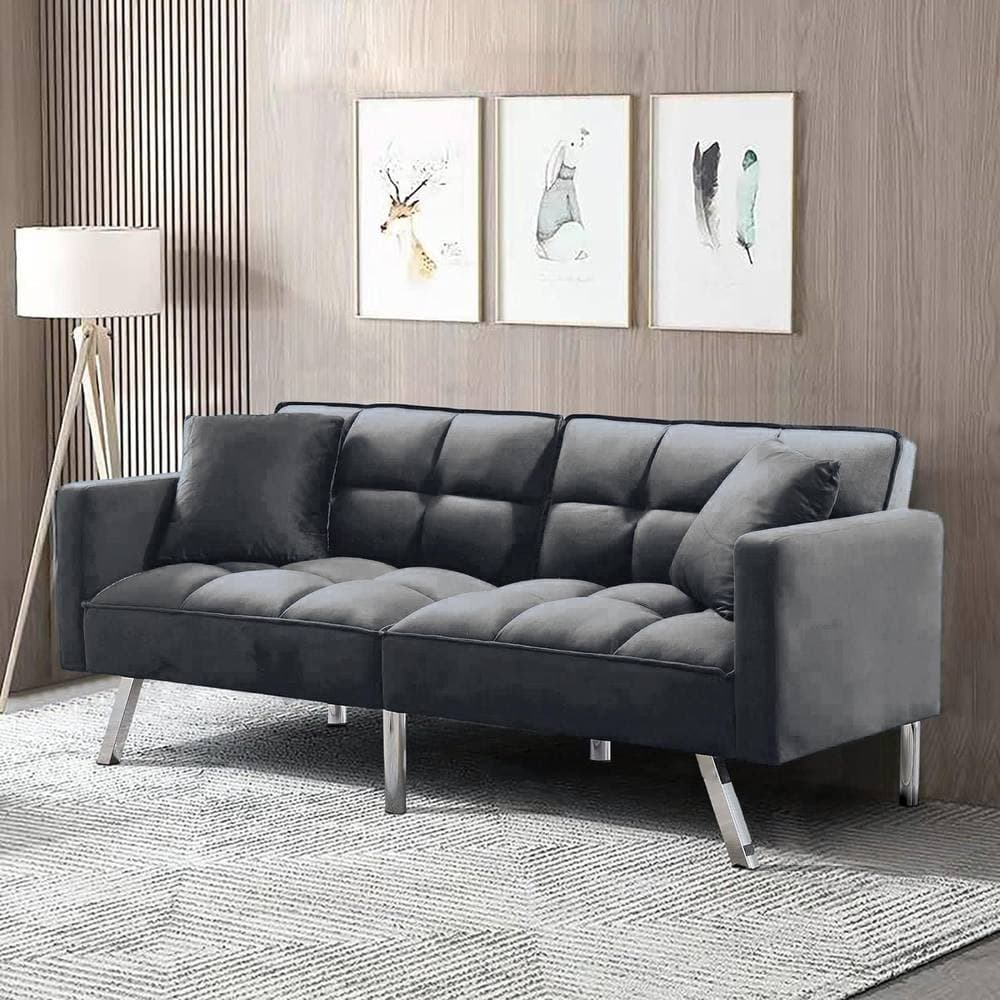 Grey velvet 2-seater sofa bed with tufted design, metal legs, and two matching pillows, set against a wooden wall and framed artwork.
