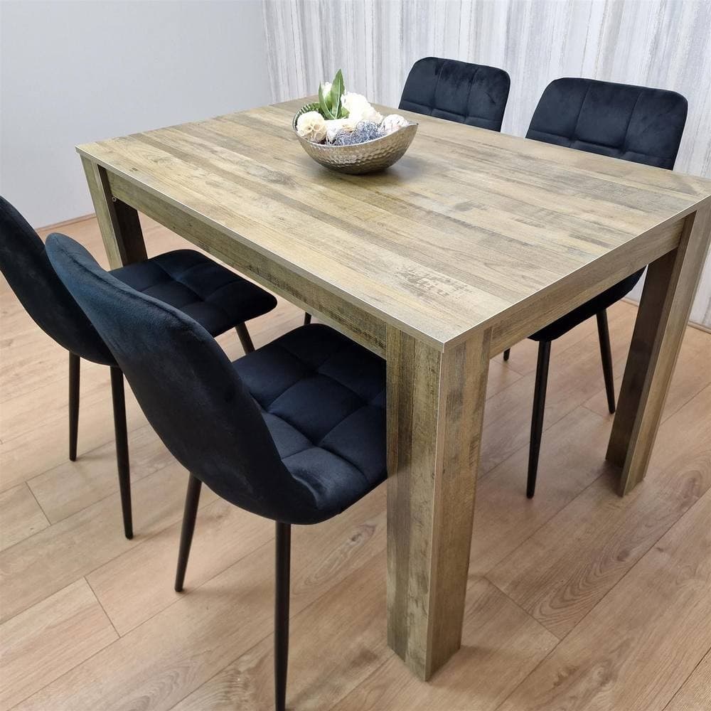 Rustic wood dining table in brown with a textured finish, accompanied by four black velvet chairs featuring a tufted design and slender black legs.