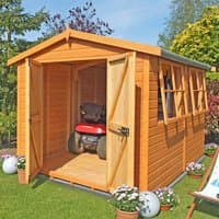 Wooden workshop with double doors, pitched roof, and side windows, set in a garden with plants and lawn.