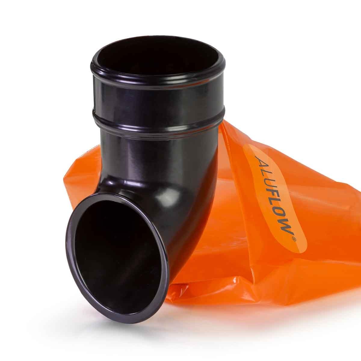 Black Aluflow downpipe shoe made of durable plastic, featuring a curved design and a wide opening, accompanied by an orange Clear Amber branded bag.