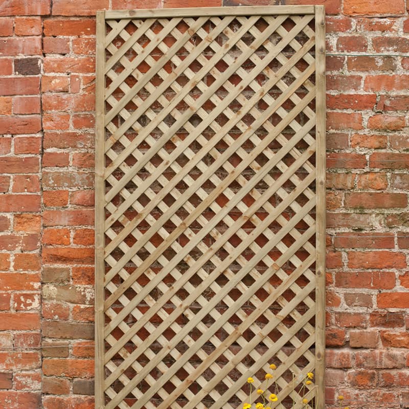 A 6' x 6' decorative diamond trellis made of pressure-treated wood, featuring a crisscross lattice design, set against a rustic brick wall.