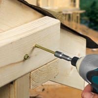 Green hex head landscaping screw being drilled into timber frame, showcasing TIMCO's durable exterior construction screws.