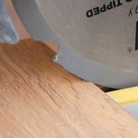 Circular saw blade with six teeth, silver finish, mounted on a saw cutting through wood.