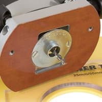 Router guide bush with a silver circular center, mounted on a brown base, marked "25mm/50mm" on a yellow surface.