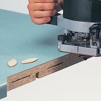 Router cutting slot in wood with Trend Slotter 11mm kerf, M12mm bore, visible biscuit joints on green laminate surface.