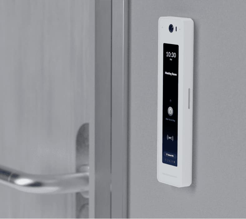 White UA-G2 UniFi Access Reader G2 Professional mounted on a wall beside a door, featuring a touchscreen display showing time and room status.