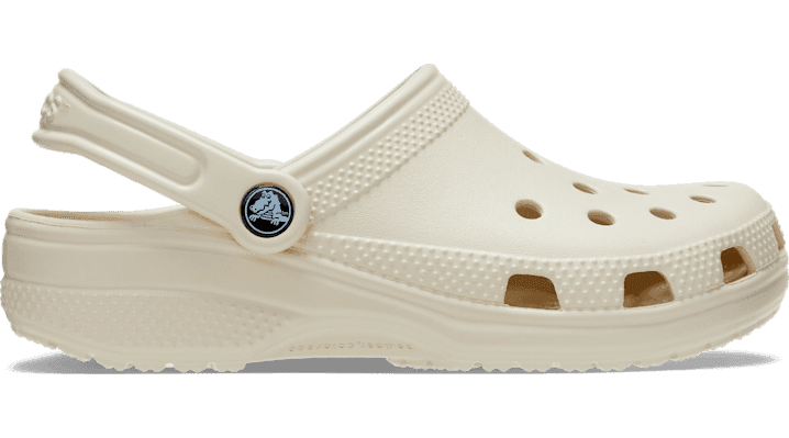 Beige CROCS Classic Unisex Clogs featuring a lightweight, durable foam material, ventilation holes, and a back strap for a secure fit.